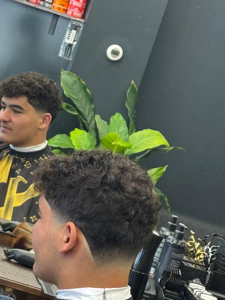 Krullen met een korte fade in de nek, gezien in de spiegel van de zaak